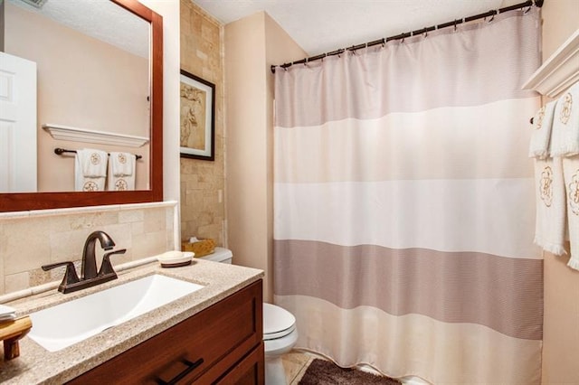 bathroom with vanity, tasteful backsplash, and toilet