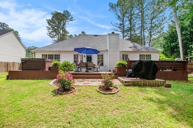 back of property with a yard, a hot tub, and a deck