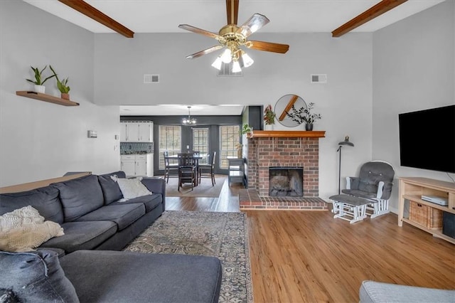 living area featuring visible vents, beamed ceiling, wood finished floors, and a fireplace