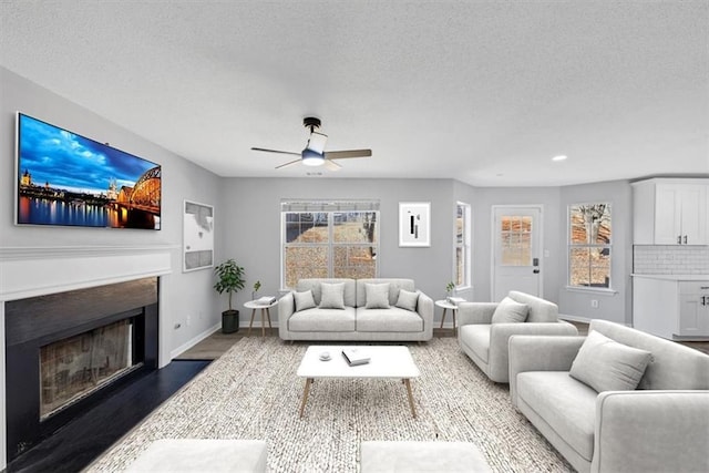 living room with ceiling fan, hardwood / wood-style floors, and a textured ceiling