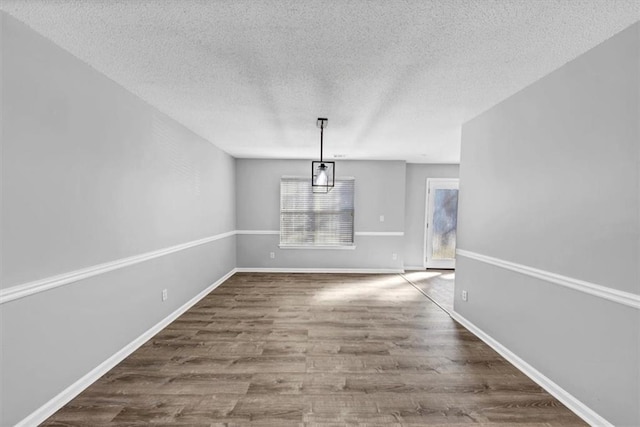 unfurnished dining area with hardwood / wood-style floors and a textured ceiling