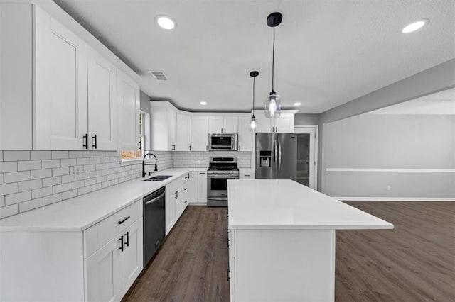 kitchen with sink, white cabinetry, decorative light fixtures, a center island, and appliances with stainless steel finishes