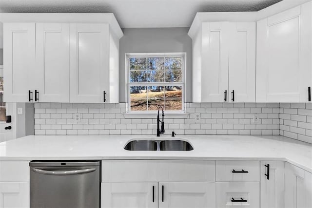 kitchen featuring white cabinetry, sink, stainless steel dishwasher, and backsplash