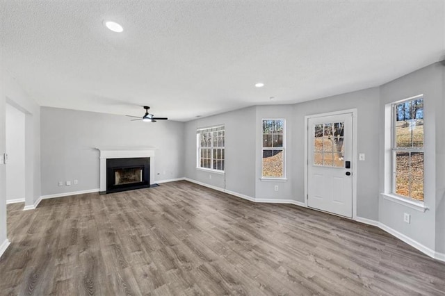 unfurnished living room with hardwood / wood-style floors, plenty of natural light, a textured ceiling, and ceiling fan