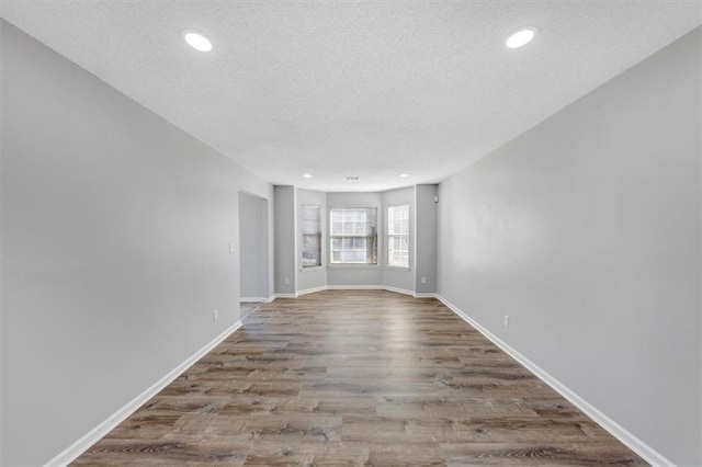 unfurnished room with a textured ceiling and light hardwood / wood-style flooring