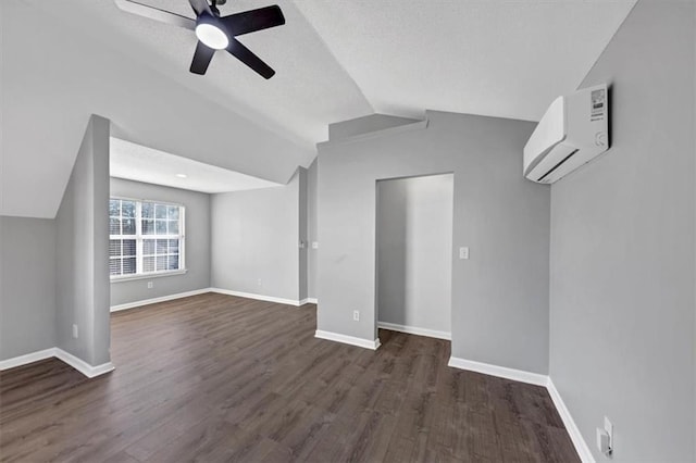 additional living space with vaulted ceiling, dark hardwood / wood-style floors, a wall mounted AC, and ceiling fan