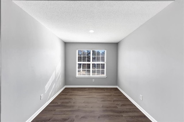 empty room with dark hardwood / wood-style flooring and a textured ceiling