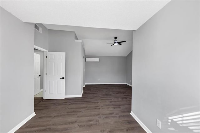 interior space featuring dark hardwood / wood-style flooring, lofted ceiling, a wall mounted AC, and ceiling fan