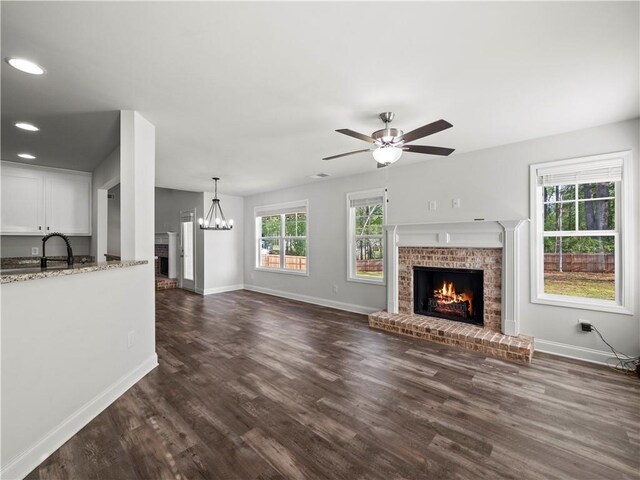 385 Finch Landing Rd, Winder, GA 30680 - unfurnished living room with a brick fireplace, baseboards, ceiling fan with notable chandelier, and dark wood-style floors