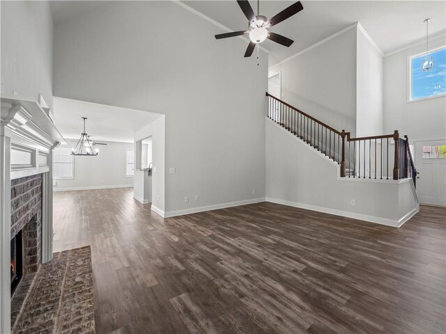 385 Finch Landing Rd, Winder, GA 30680 - unfurnished living room featuring dark wood-type flooring, high vaulted ceiling, a brick fireplace, and ceiling fan with notable chandelier