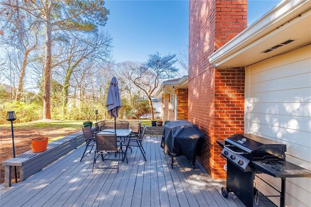 wooden terrace featuring outdoor dining area and a grill