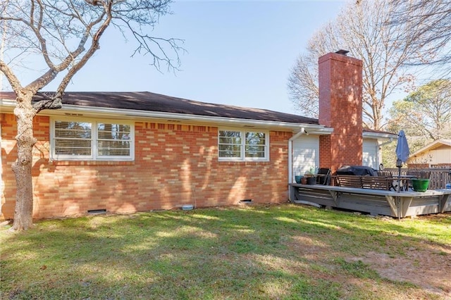 rear view of house with a wooden deck, a chimney, crawl space, a yard, and brick siding