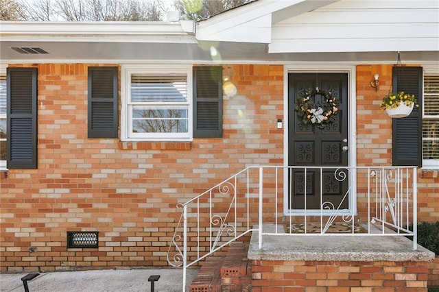 property entrance featuring crawl space, brick siding, and visible vents