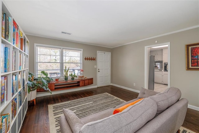 living area with ornamental molding, wood finished floors, visible vents, and baseboards