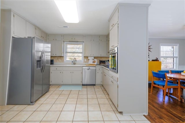 kitchen featuring light tile patterned floors, light countertops, decorative backsplash, appliances with stainless steel finishes, and a sink