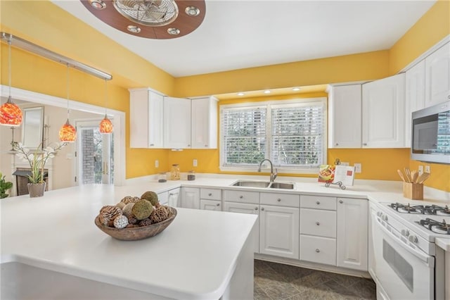 kitchen featuring white range with gas stovetop, a sink, white cabinets, a wealth of natural light, and stainless steel microwave