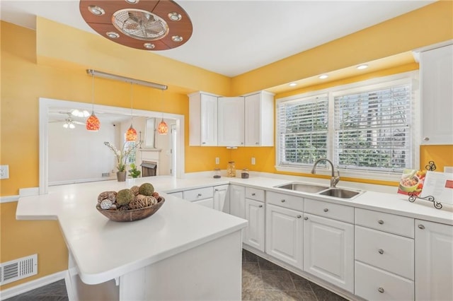 kitchen with visible vents, light countertops, white cabinetry, pendant lighting, and a sink