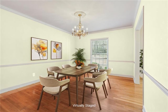 dining room featuring light wood-style floors, ornamental molding, baseboards, and an inviting chandelier