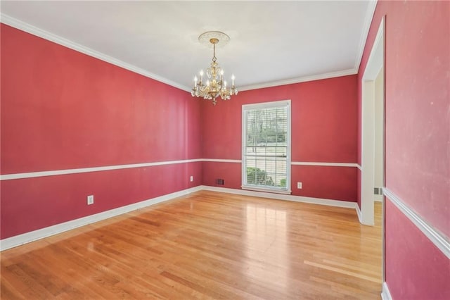 empty room featuring baseboards, ornamental molding, wood finished floors, and a notable chandelier