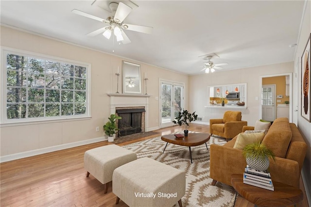 living area featuring a fireplace with flush hearth, ceiling fan, wood finished floors, washer / dryer, and baseboards