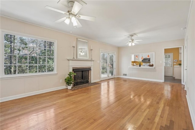 unfurnished living room with light wood-type flooring, ceiling fan, visible vents, and a fireplace with flush hearth