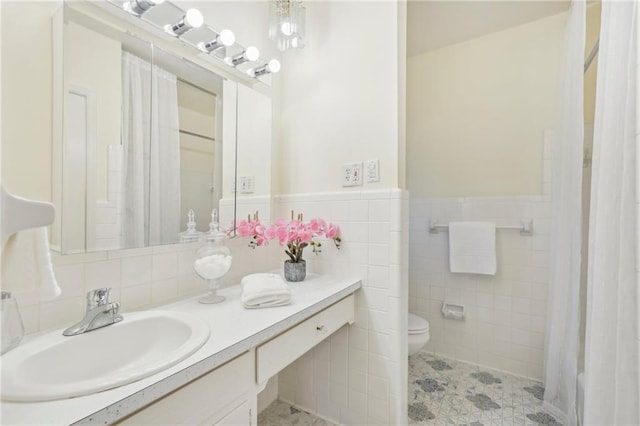 full bath featuring toilet, a wainscoted wall, tile walls, and vanity