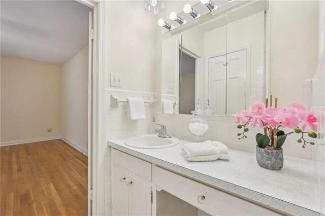 bathroom featuring tasteful backsplash, wood finished floors, vanity, and baseboards