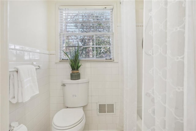 full bathroom featuring visible vents, tile walls, and toilet