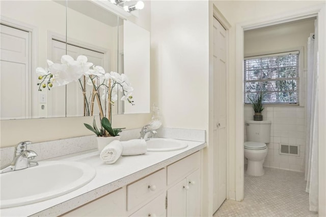 bathroom featuring toilet, a sink, visible vents, and tile patterned floors