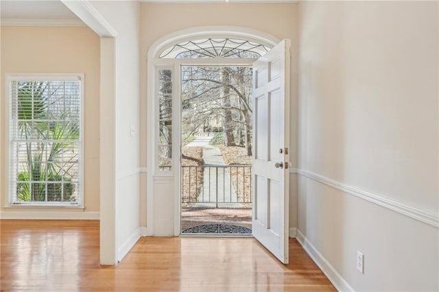 entryway featuring crown molding, baseboards, wood finished floors, and a healthy amount of sunlight