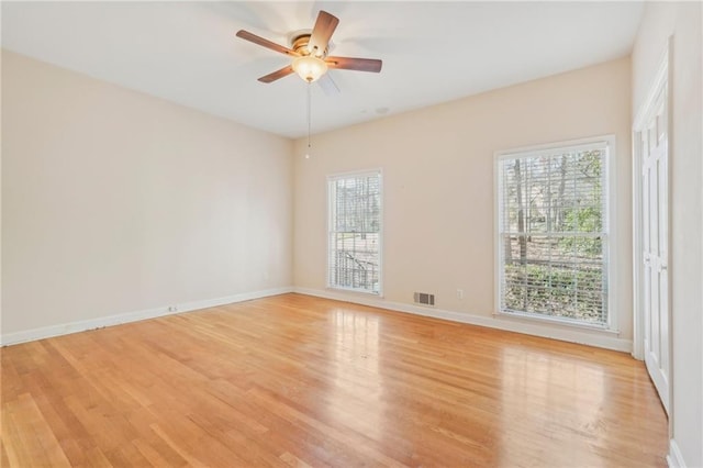 spare room featuring light wood-type flooring, visible vents, ceiling fan, and baseboards