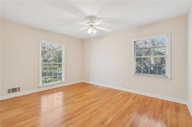 empty room with a ceiling fan, light wood-type flooring, visible vents, and baseboards