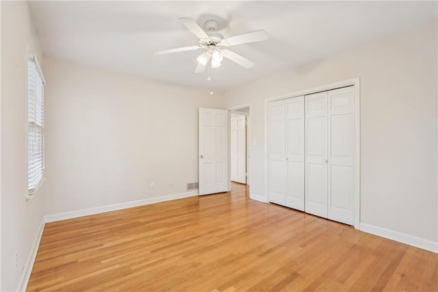 unfurnished bedroom featuring multiple windows, light wood-style flooring, and baseboards