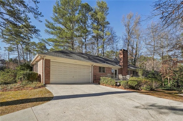 view of side of home featuring a garage, concrete driveway, brick siding, and a chimney