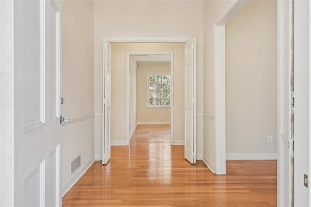 corridor with visible vents, light wood-style flooring, and baseboards