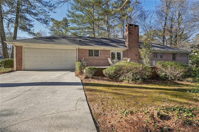 ranch-style home with brick siding, a chimney, a front yard, a garage, and driveway