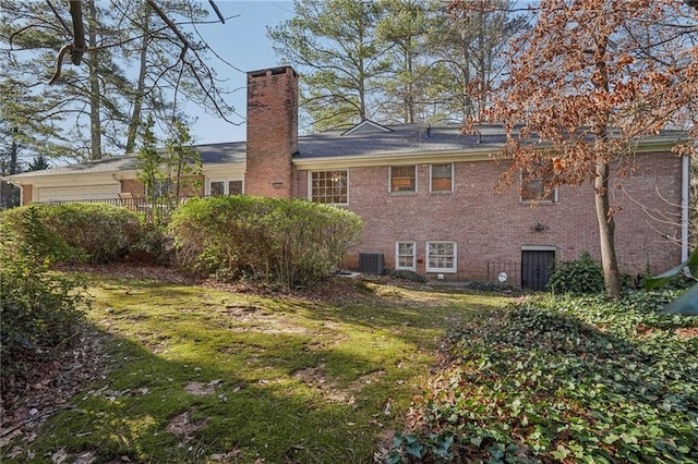 back of house with central air condition unit, a chimney, and brick siding