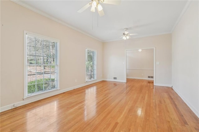 empty room with ornamental molding, light wood-type flooring, and baseboards