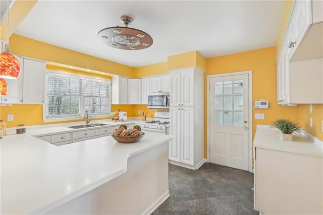 kitchen with light countertops, stainless steel microwave, a sink, and white range with gas cooktop