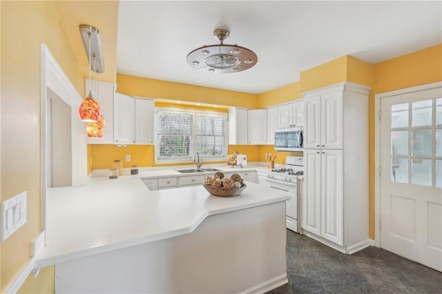 kitchen featuring a peninsula, a sink, white range with gas cooktop, light countertops, and stainless steel microwave