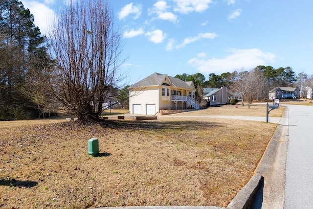 view of front of home featuring stairway, an attached garage, a residential view, and a front yard