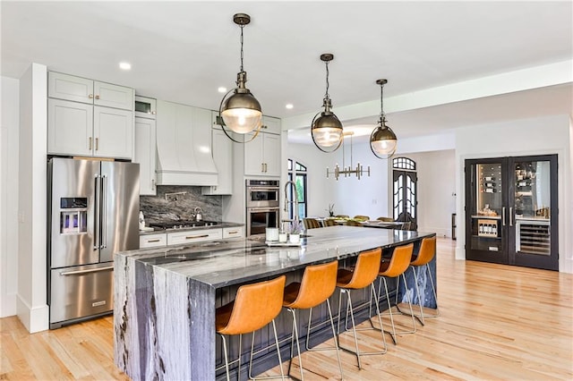 kitchen featuring a kitchen island with sink, a breakfast bar area, stainless steel appliances, dark stone counters, and backsplash