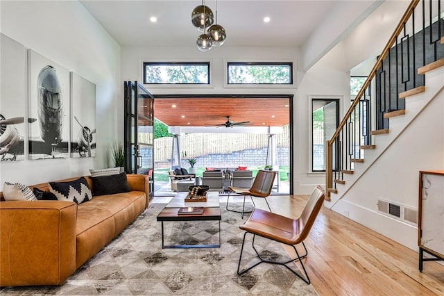 living room with a high ceiling, a wealth of natural light, ceiling fan, and light hardwood / wood-style floors