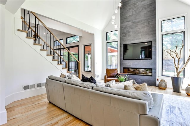 living room featuring a high ceiling, a large fireplace, and light wood-type flooring