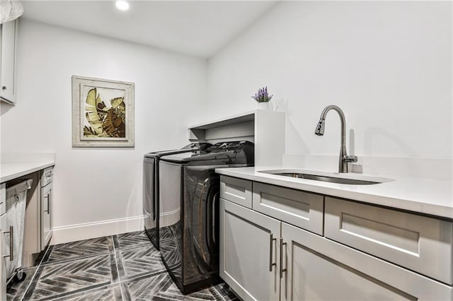 clothes washing area with sink, washer and clothes dryer, and cabinets