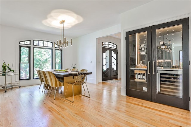 dining area with french doors, light hardwood / wood-style floors, and a chandelier