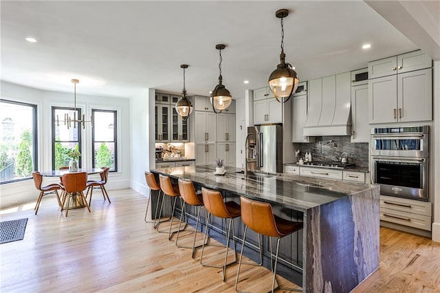 kitchen featuring dark stone countertops, appliances with stainless steel finishes, a spacious island, decorative light fixtures, and backsplash