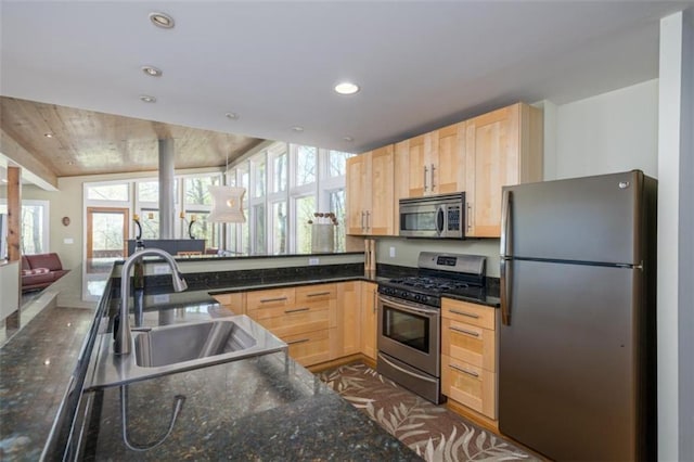 kitchen featuring a sink, light brown cabinets, open floor plan, and appliances with stainless steel finishes
