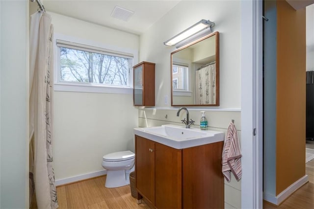 bathroom featuring toilet, wood finished floors, vanity, visible vents, and baseboards