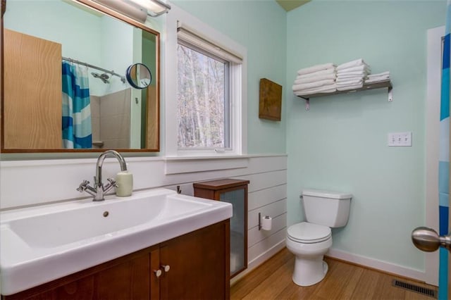 bathroom featuring toilet, wood finished floors, vanity, curtained shower, and visible vents
